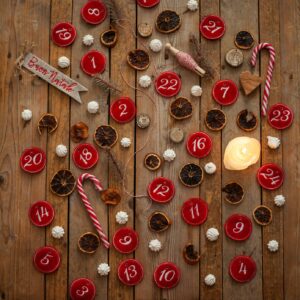 fondale in legno su cui sono state adagiate delle tag in panno che riportano i numeri del calendario dell'avvento