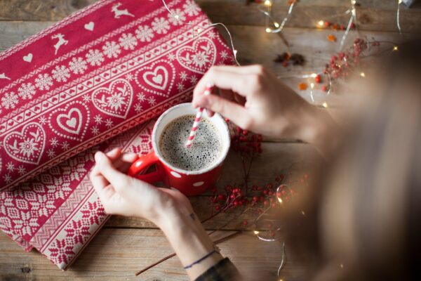 mani di donna che mescolano il caffè, attorno elementi natalizi